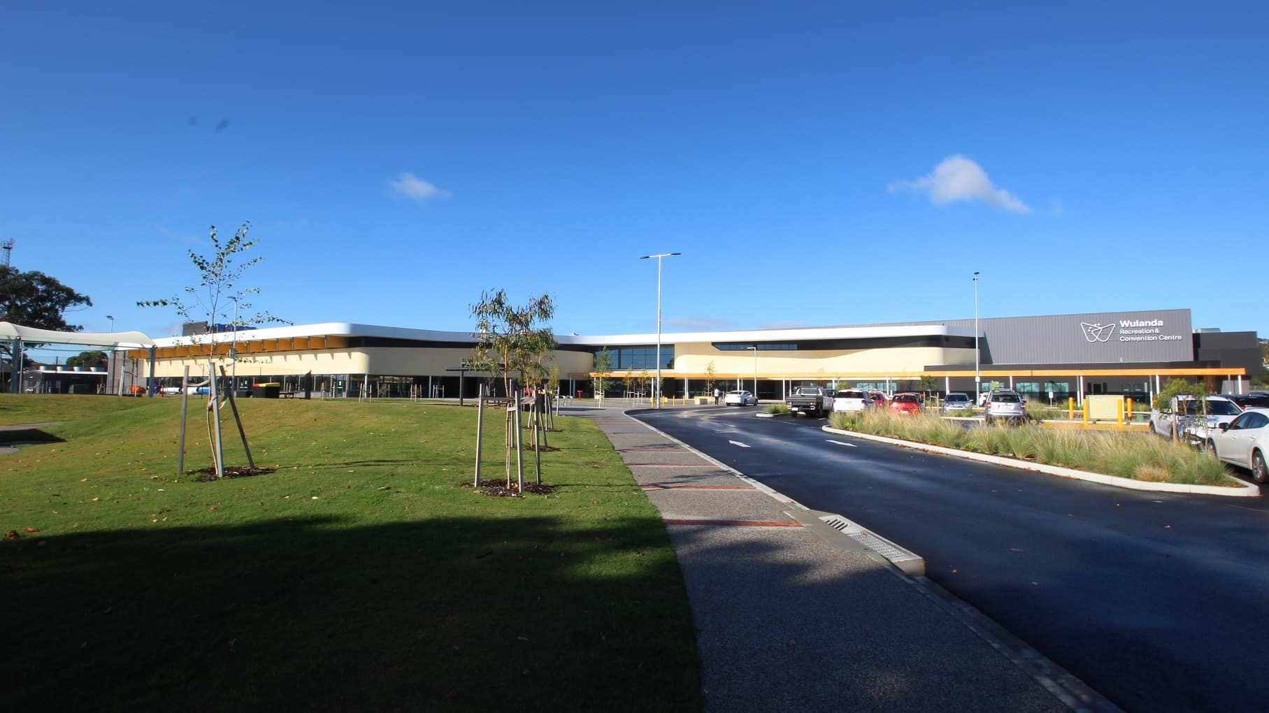 Wulanda Recreation & Convention Centre is a large low set building on an open expansive sports reserve. The building is a modern sports complex design with natural colour schemes with creams, whites and grey. The adjoining carpark has recently been planted with trees to provide shade in time. The main entrance is in the middle of the facility via step free pathways from the carpark.