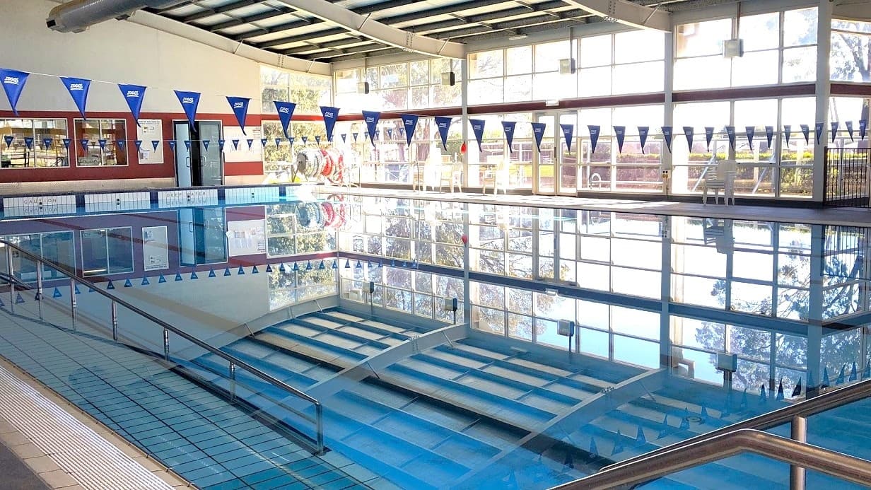 Swan Hill Leisure Centre is a low set grey and blue building that is nestled amongst lush green trees. Access to the centre is via Pritchard Street with parking available in close proximity to the entrance, including a number of accessible car spaces.