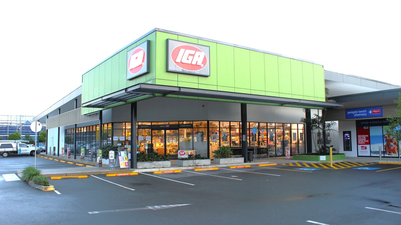 White’s IGA Peregian Beach Shopping store. The exterior of the building is green, black, and grey. Half of the wall is made of glass. Two IGA brand logo is placed at the top of the building adjacent to each other. Left side of the building is the Peregian Beach Pharmacy.