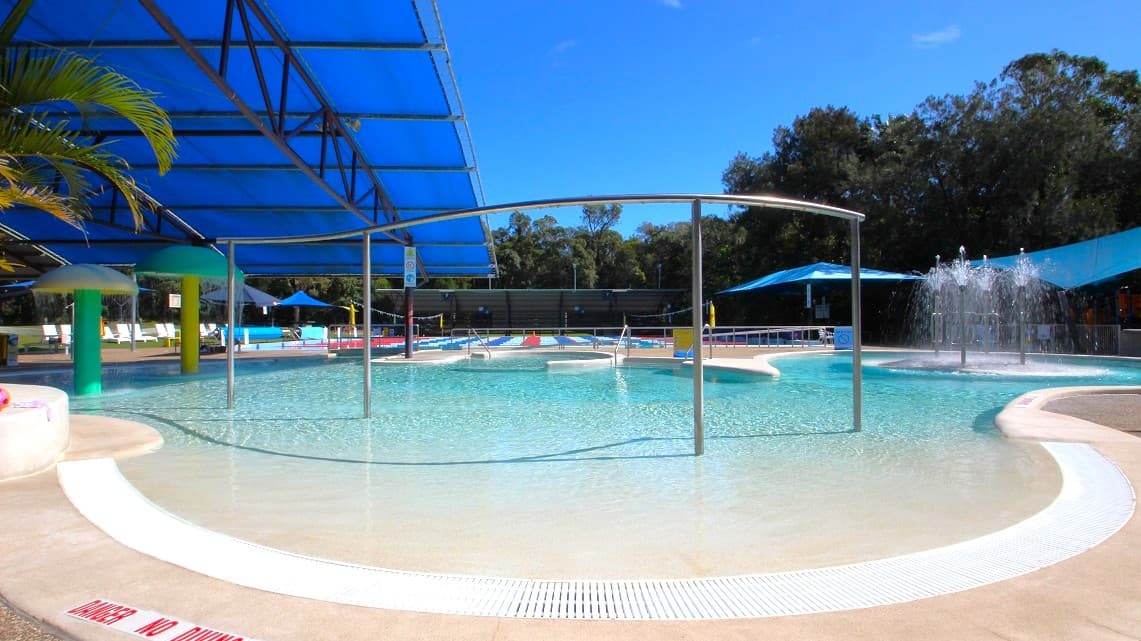 The Bribie Island Aquatic and Leisure Centre is an amazing open-air aquatic facility nestled in the midst of coastal bushland and forest. It's a charming, low-set building with long curved lines and a roof made of corrugated iron. The carpark offers two convenient accessible car spaces, along with plenty of shade and a step-free entrance.