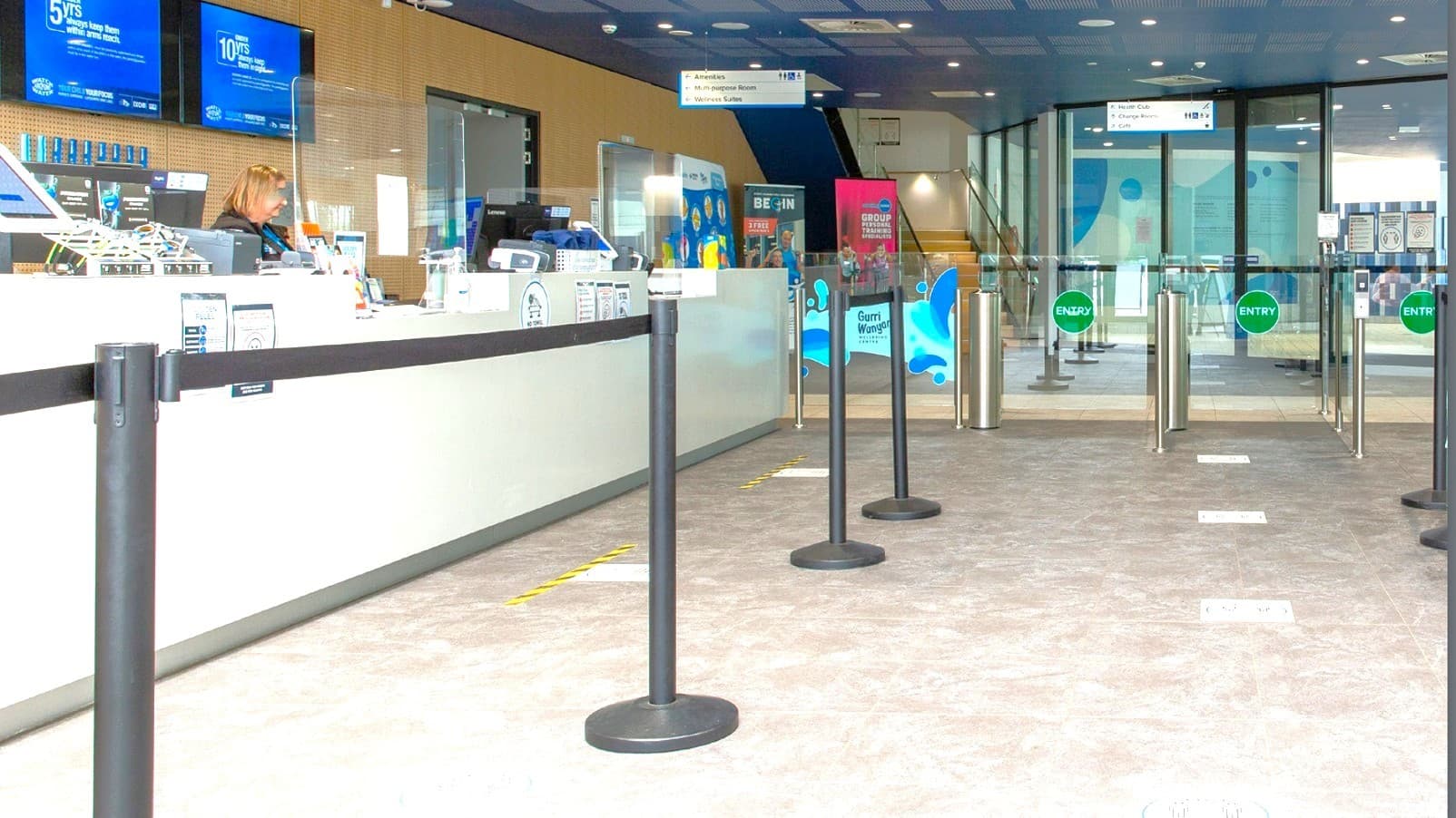 A woman wearing a black polo at the reception desk will welcome you to Gurri Wanyara. The reception area has handrails for guiding guests to follow the line. Yellow and black strips on the floor indicate where you must stand while talking to the receptionists.