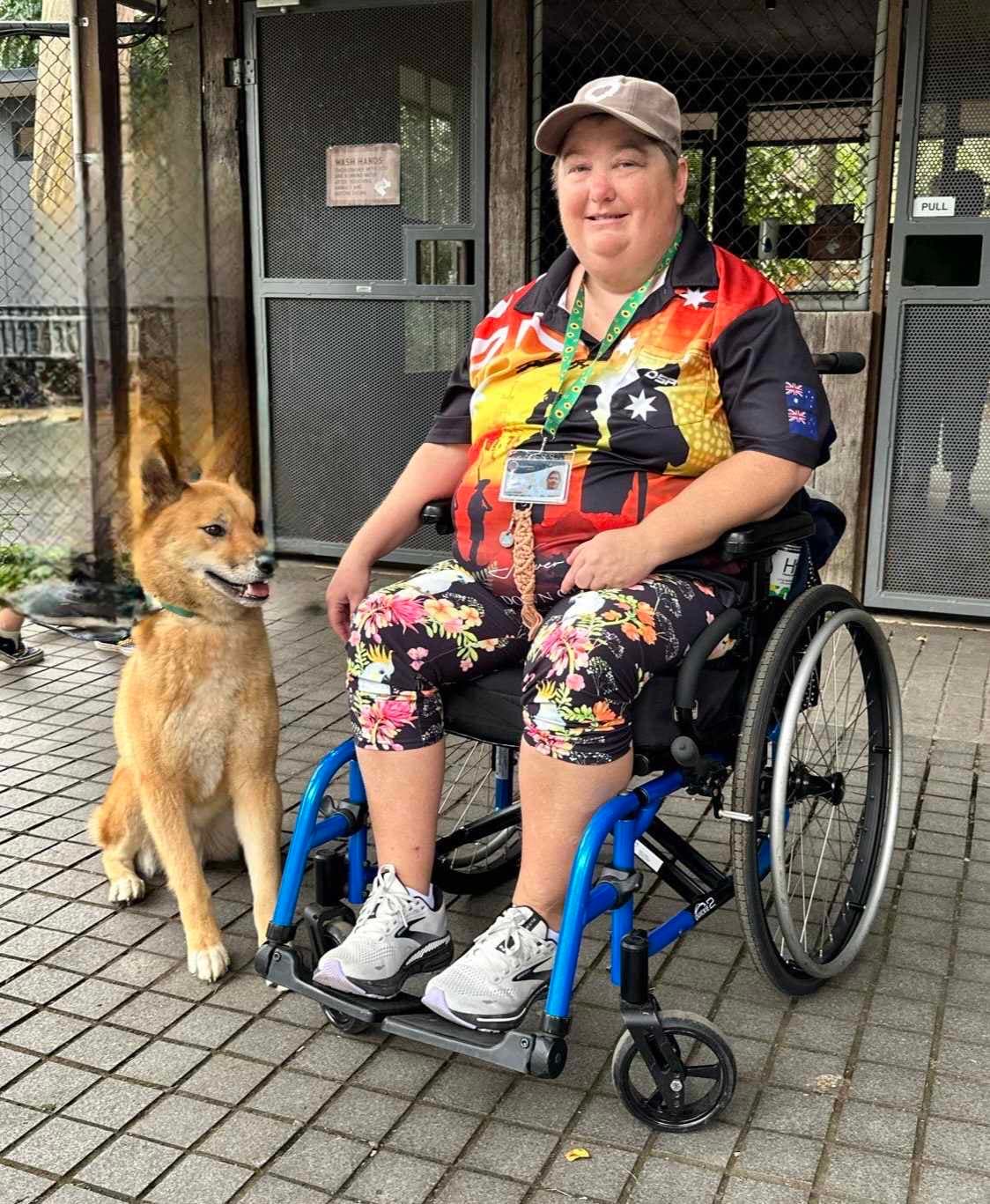 A person in a wheelchair with a dog by their side, both outdoors.