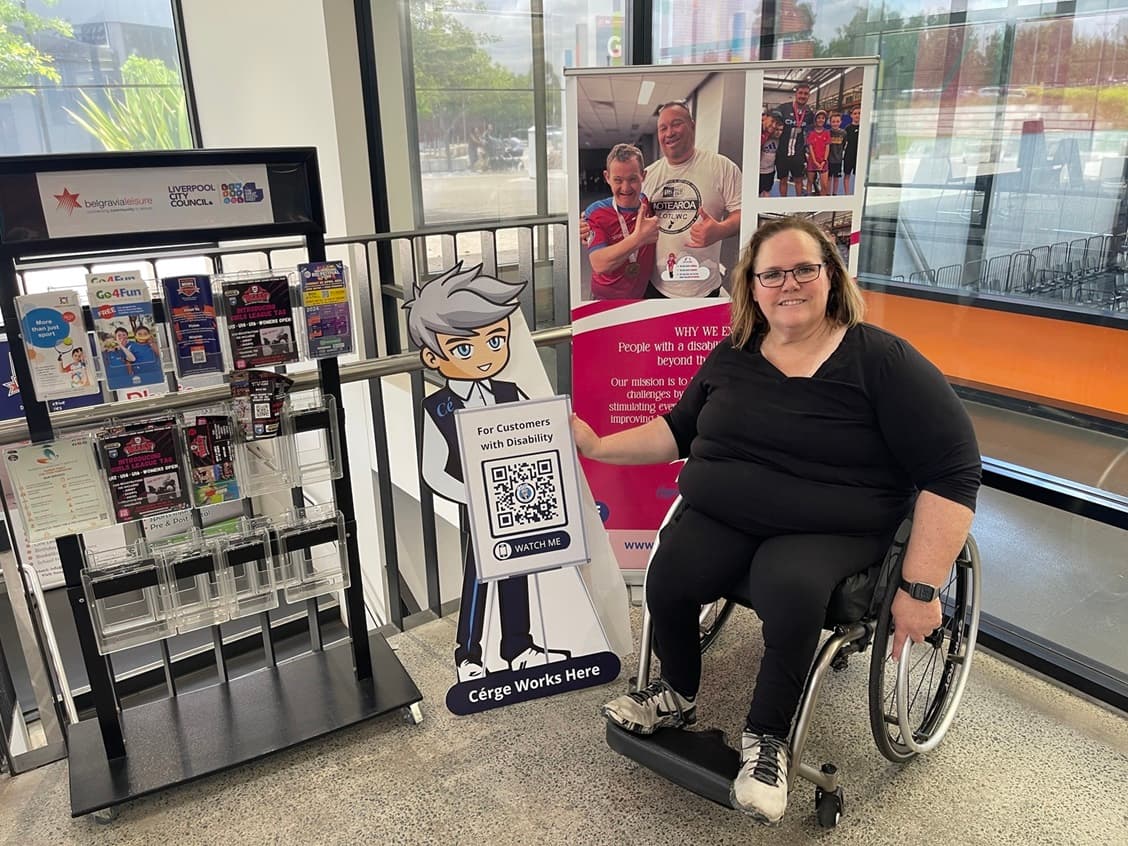 A woman in a wheelchair sits beside a display at a store.