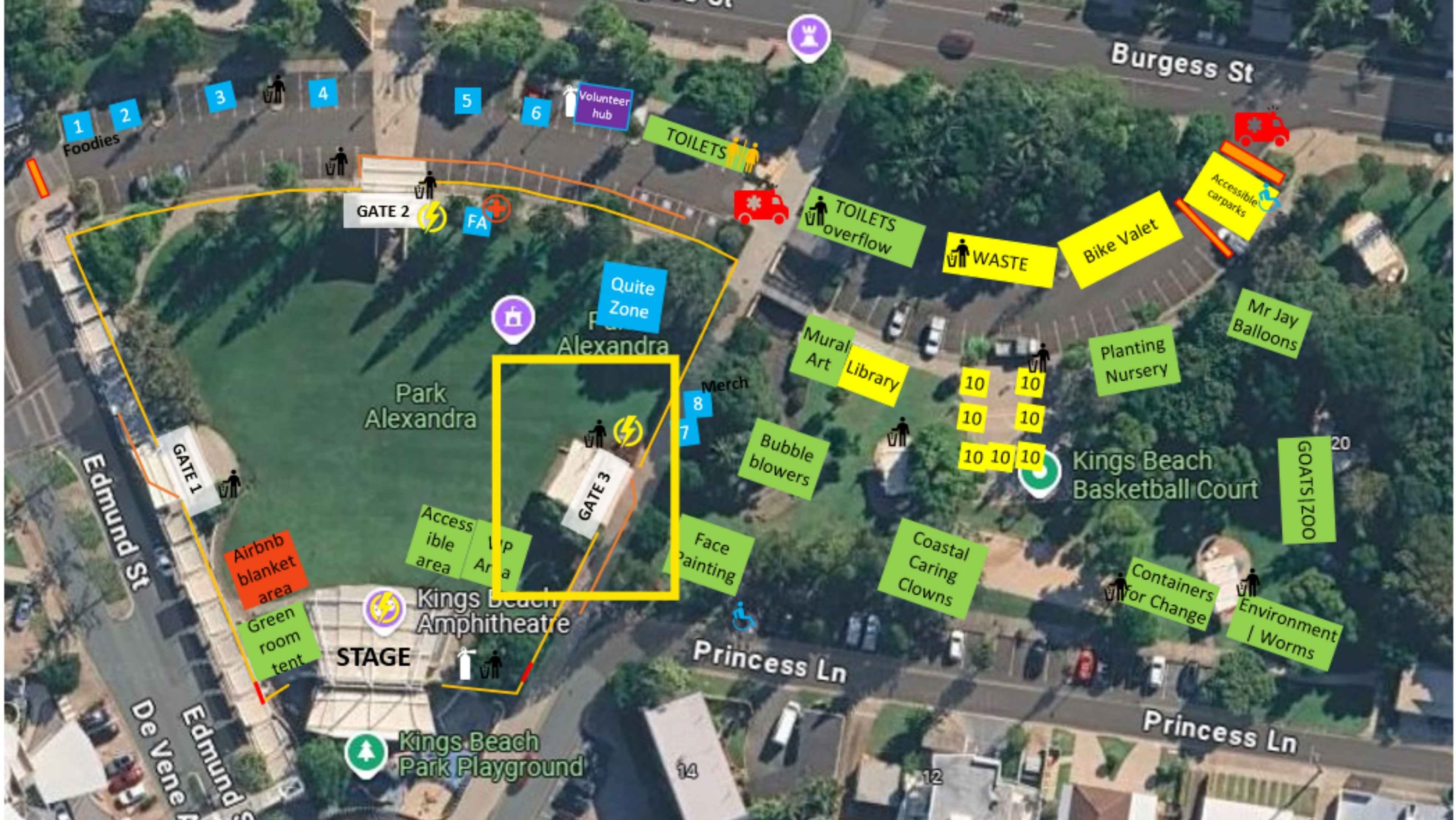 Aerial view of a park event with a yellow square marking a central building. Left foreground shows a curved road, a red “Airbnb blanket area” label, and a stage area near the park's edge. Right foreground features a cluster of green and yellow signs, with a basketball court nearby and a library area. Background includes tree-lined streets, a car-filled car park, and surrounding pathways. Floor is grass with paved paths and scattered signage; ceiling not applicable.