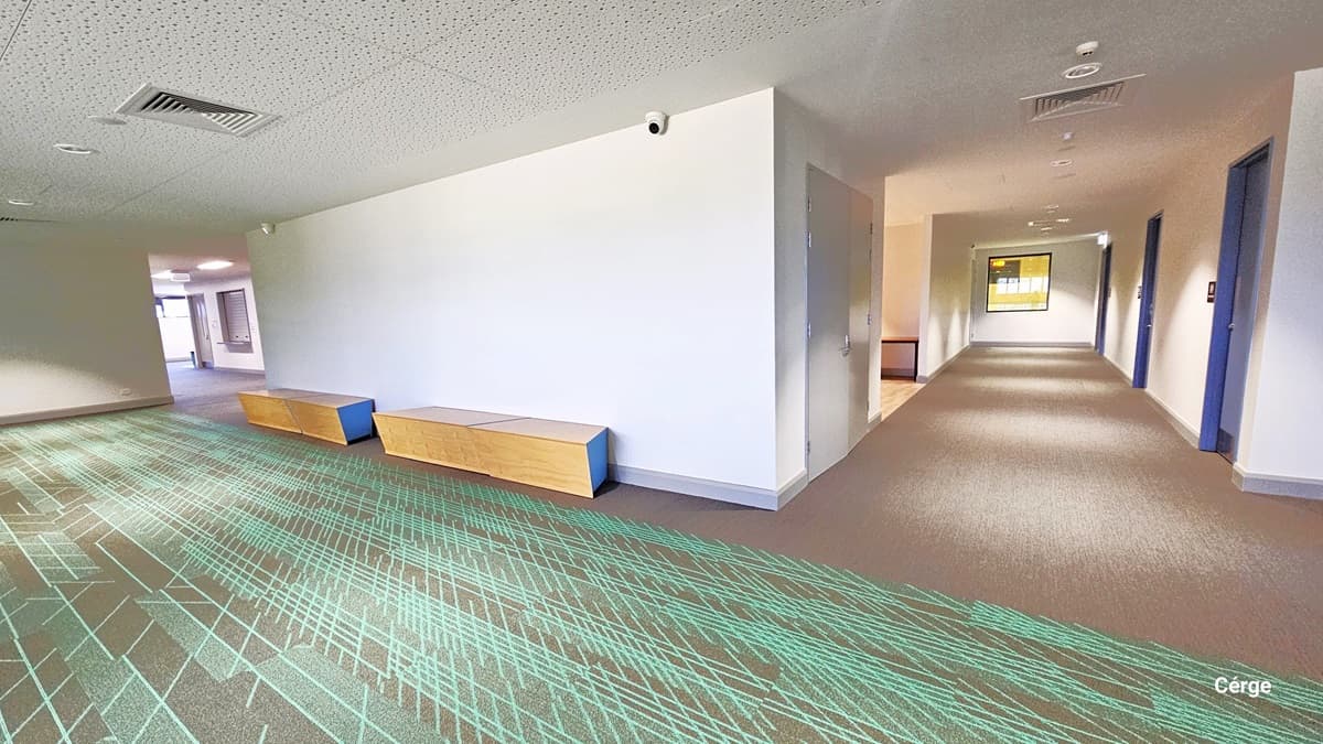 Level One, is a roomy space with yellow and blue wooden benches. The floor exhibits granite with green criss-cross markings. Above, the white ceiling hosts fluorescent bulbs and central air conditioning. To the right, a lobby grants access to three rooms, while the left leads to open glass windows.