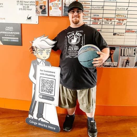A man in a black shirt and shorts stands beside a cartoon cutout with a QR sign and a basketball.