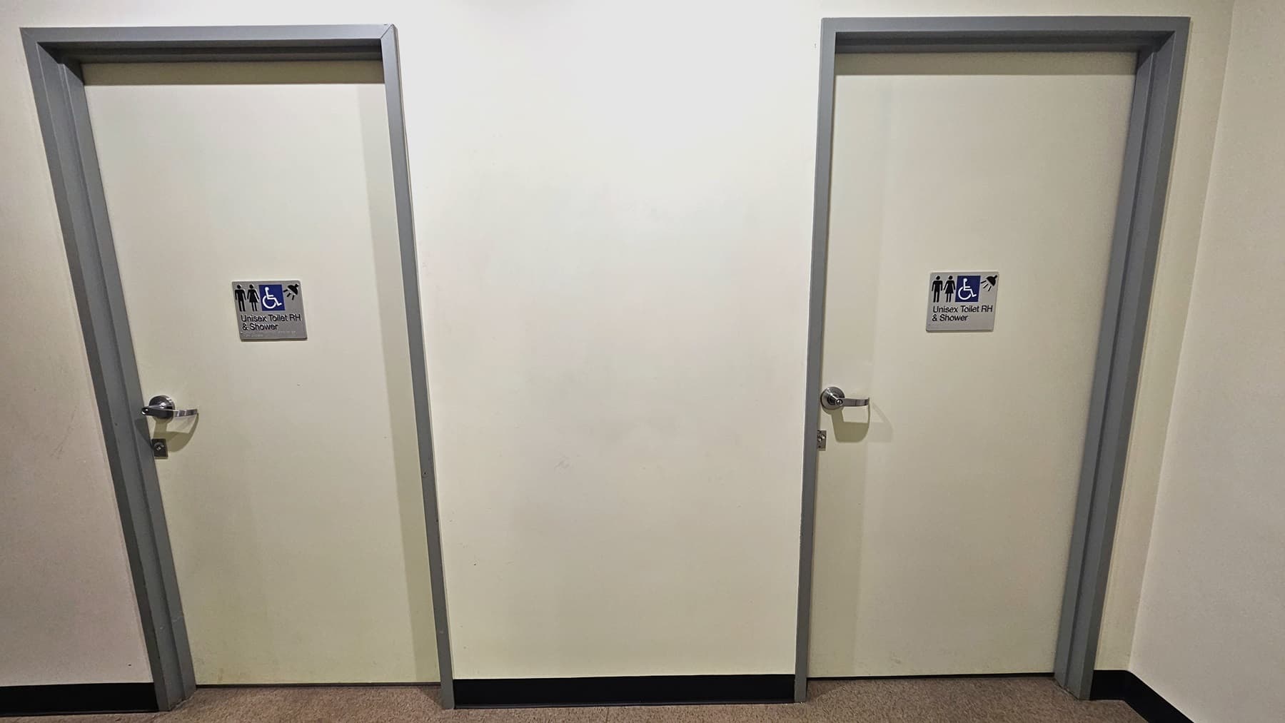 There are two accessible all-gender bathrooms with showers located near the gymnasium. Each white door is marked with signage in front.
