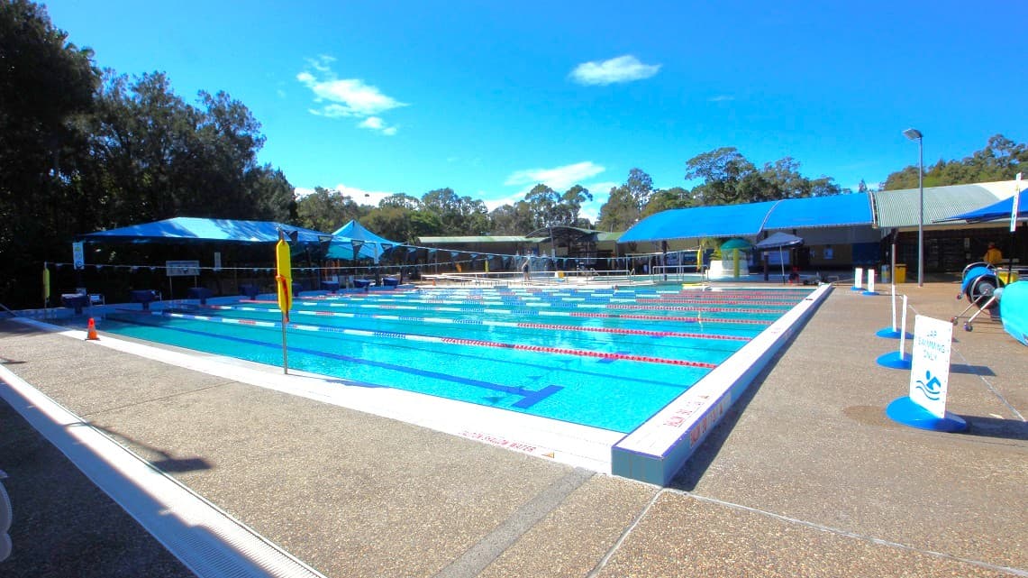 Another look at the expansive swimming pool inside the Bribie Island Aquatic and Leisure Centre. It's wide and perfect for lap swimming. There are signs reminding visitors that only lap swimming is allowed in this pool area. Surrounding the entire open-air aquatic area, you'll see tall trees, adding a natural and refreshing ambiance.