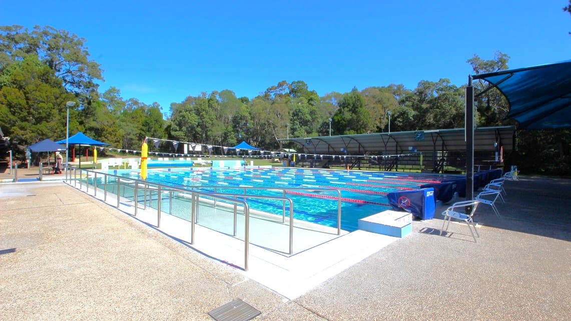 Taking another look at the wide swimming pool of the Bribie Island Aquatic and Leisure Centre, there are safety railings on the left side for added security. Each narrow area of the pool is equipped with metallic chairs for guests to relax. The presence of tall and huge trees on this side adds to the picturesque surroundings.