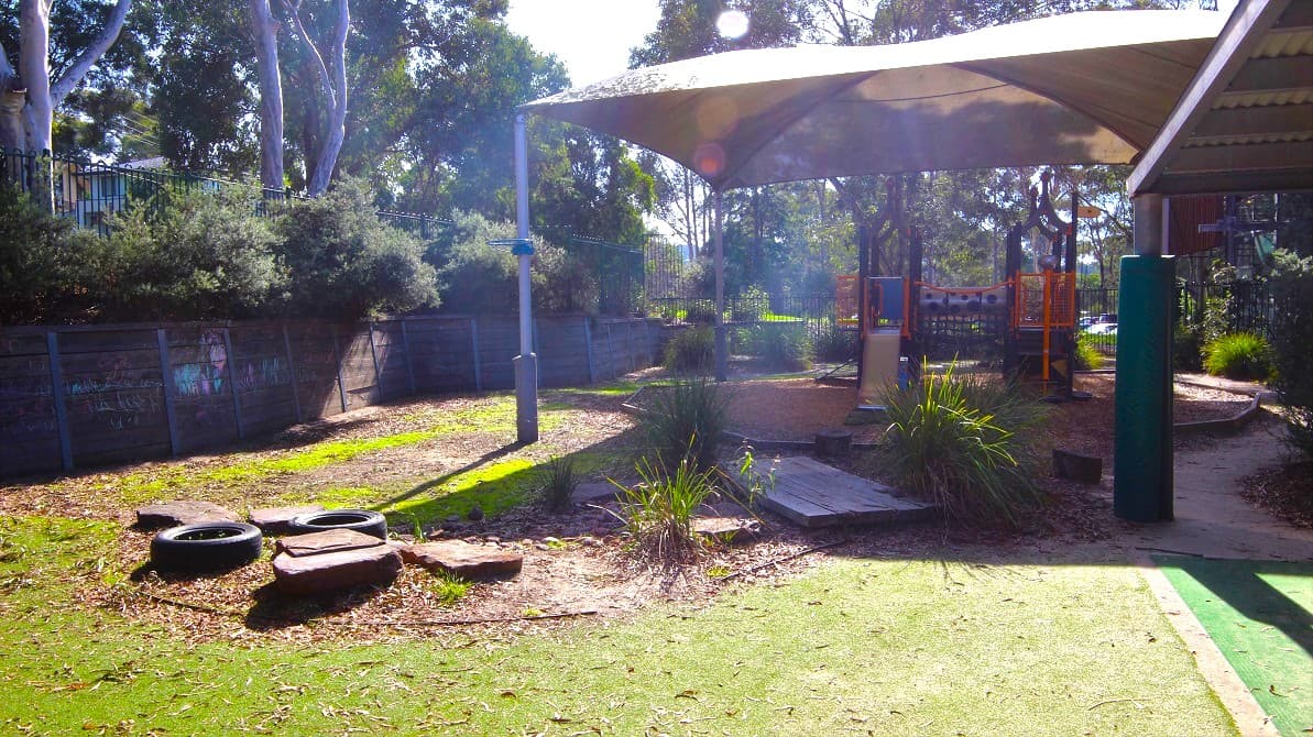 A grass area near an obstacle course and a sand pit play area. The sand pit play area is covered by a large tent that provides enough shade. The venue is also surrounded by tall trees that give fresh air to your children.