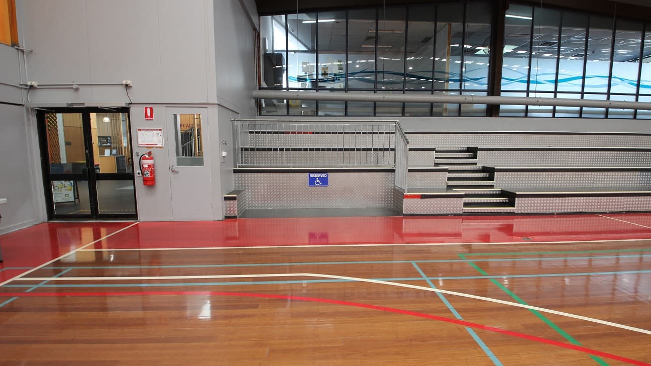 Lower, section of the left and right side of the stadium is a space dedicated or reserved for persons with disability. Further left is the exit door and fire extinguisher mounted on the wall near it.