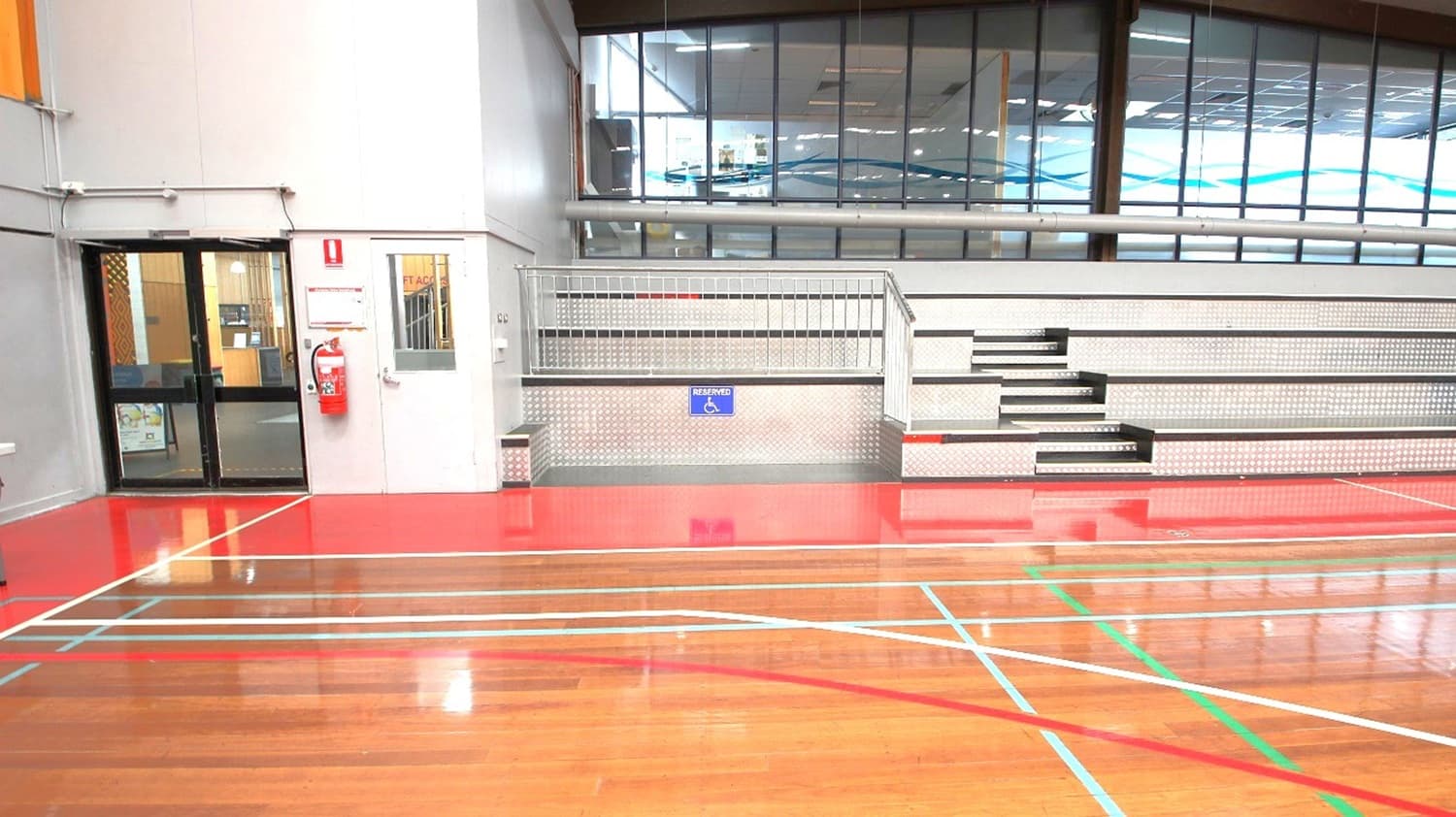Lower, section of the left and right side of the stadium is a space dedicated or reserved for persons with disability. Further left is the exit door and fire extinguisher mounted on the wall near it.
