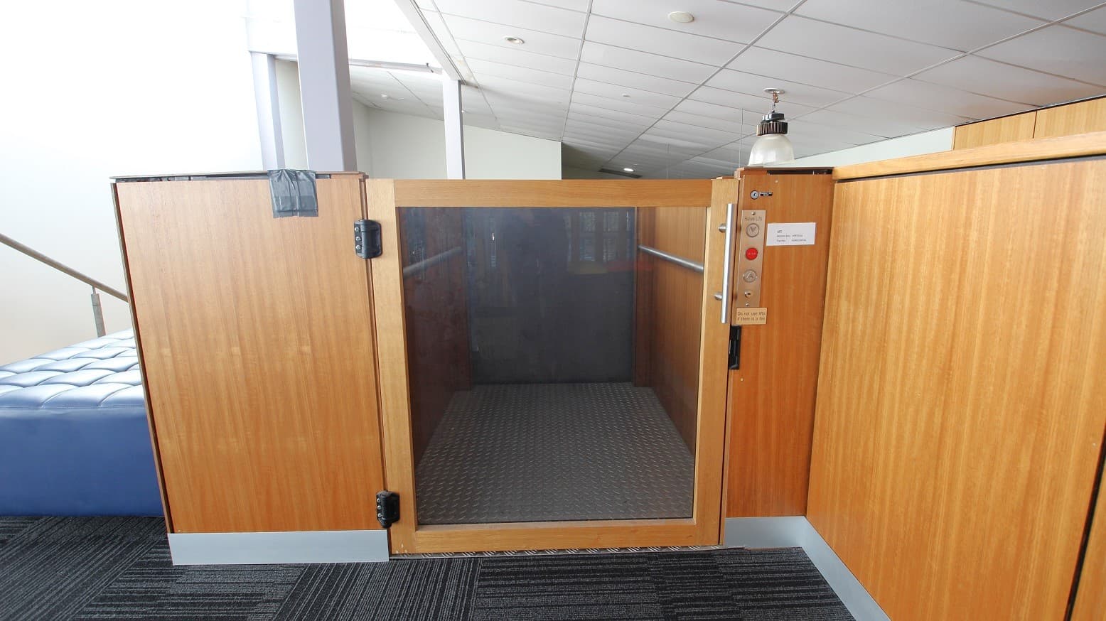 Elevator is made of timber and silver-grey metal and is equipped with Up, Down, and Stop buttons indicated by the red circle in the middle.