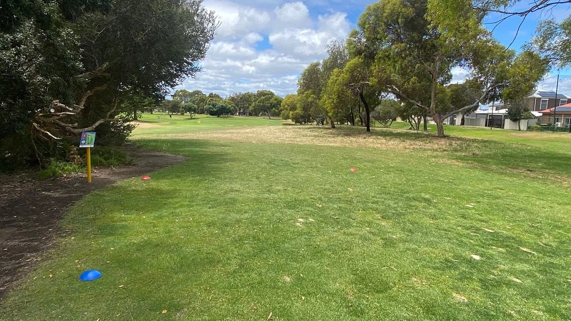 Another large and healthy vegetation space at Glanville Hall Golf Course. The left side of the image shows a tree with dense green foliage and a signboard with a map of the area, while the right is the local residential units.
