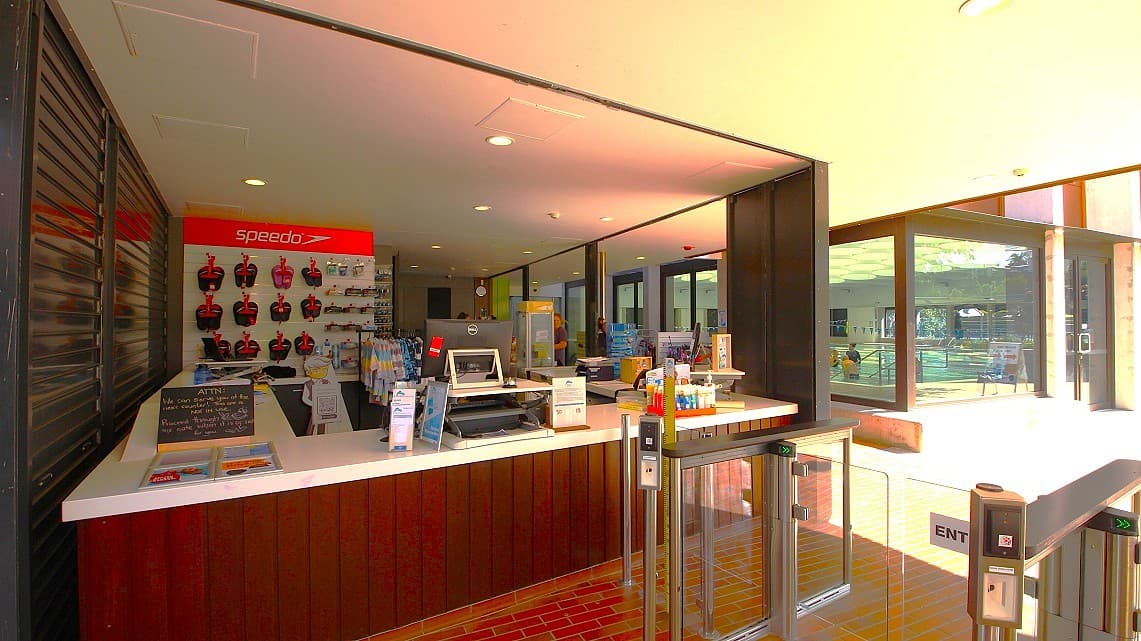 A closer look at the reception area. Inside the reception area, fluorescent lighting floods the space, ensuring ample illumination. You'll find essential items like swimming slippers and backup swimwear readily available, making it convenient for visitors. Before entering the interior of the ARC, there are noticeable metal grill doors that add to the modern and secure atmosphere of the facility.