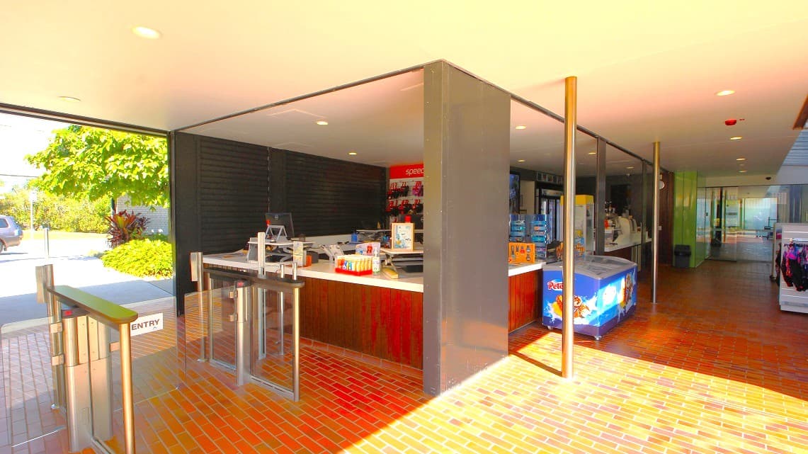 Another angle of the front entrance. Prominent brick floor tiles and metal grill doors near the reception area create a rustic-modern contrast. A wide, spacious right-side pathway enhances accessibility, while the presence of a visible batch freezer suggests a focus on food service or hospitality.