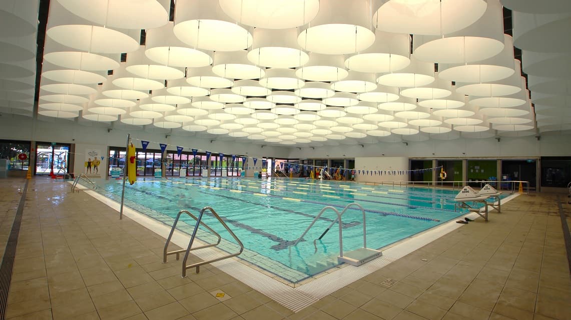Another angle of the indoor heated pool. The step access to the pool is conveniently situated beside one of the safety pool railings, making it easily accessible for swimmers. The indoor pool itself is quite expansive, mirroring the spaciousness of the surrounding pathways, providing ample room for various aquatic activities.
