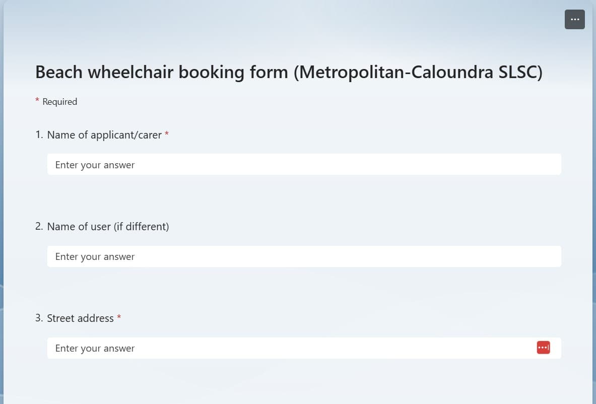 A digital booking form with a light blue background. At the top centre is the title: "Beach wheelchair booking form (Metropolitan-Caloundra SLSC)" in dark text. Below, there are three fields: "Name of applicant/carer", "Name of user (if different)", and "Street address", each with a text entry box. The first and third fields are marked with a red asterisk to indicate they are required. In the bottom-right corner of the final field, there is a red icon with three dots.