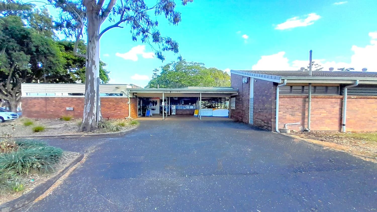This is the view of the asphalted road with a speed bump facing the centre’s main entrance. A left turn will lead you to the carpark area. A small reception area and a retail store can be found in between the two low set buildings. The facility is made of brown brick walls and surrounded by large trees.