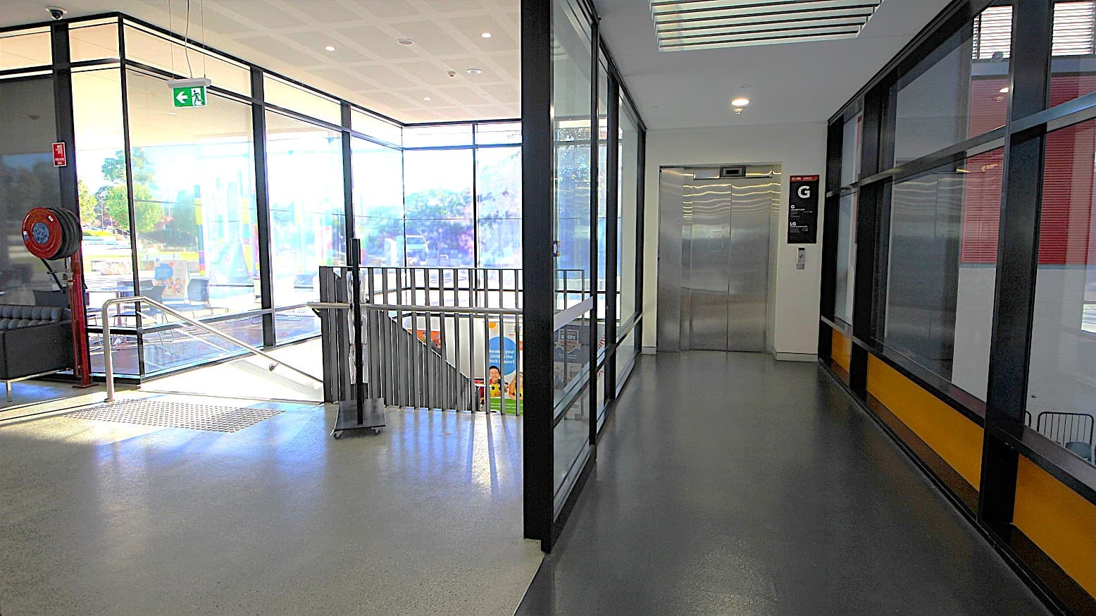Elevator access to the gym and multipurpose rooms at the Michael Clarke Recreation. It can be distinguished by the black floor right beside the black stairwell access. On the upper right of the elevator are Ground (G) and Lower Ground (G) labels. At the middle of the topmost of the elevator doors is the display screen where you can track which floor the elevator is currently on.