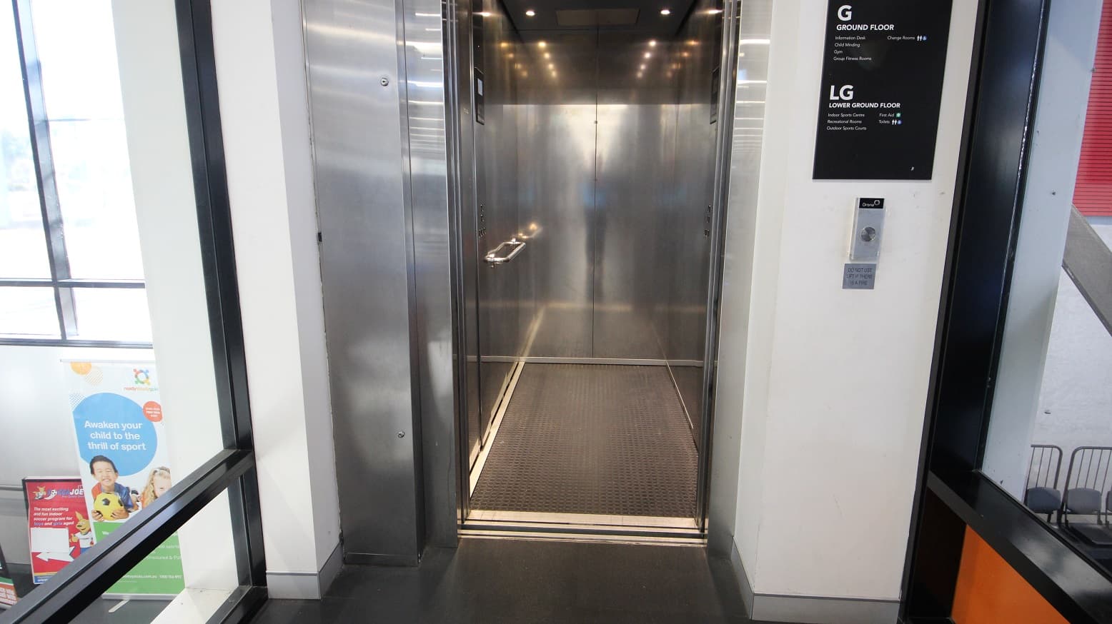A closer look at the elevator access to the gym and multipurpose rooms at Michael Clarke Recreation. On the right side of the elevator is a caution to not use the lift when there is fire. Under the “Ground” and “Lower Ground” labels on the right side of the elevator are the different amenities found on that specific floor.