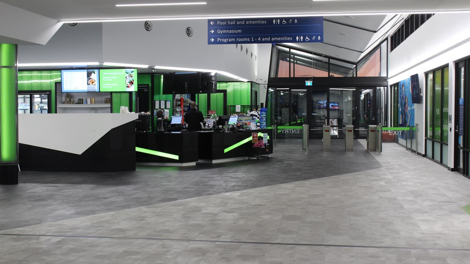 Open space directly opposite the entrance doors and next to the reception desk and Cafe area. This floor has grey tiles and white ceilings with an adequate amount of artificial fluorescents. Hanging on the ceiling is a blue rectangular signboard with arrows pointing in which direction are the different amenities located inside Mill Park Leisure.