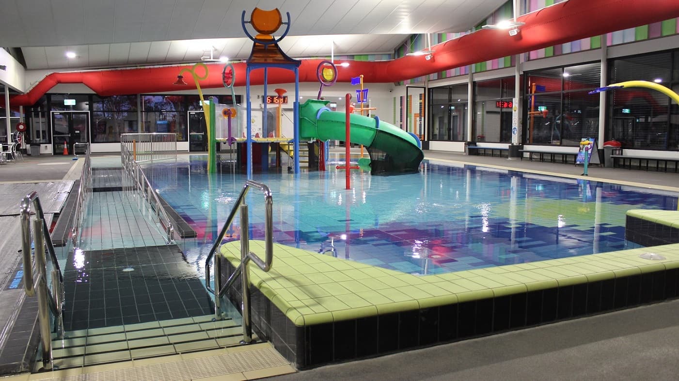 Glass automated doors to the Pool Hall. Similar to the main entrance of Mill Park Leisure, another set of conditions of entry is placed on the right side of the glass walls. Noticeable inside the pool hall is the varying size of holes with glass on the upper part of the white wall.