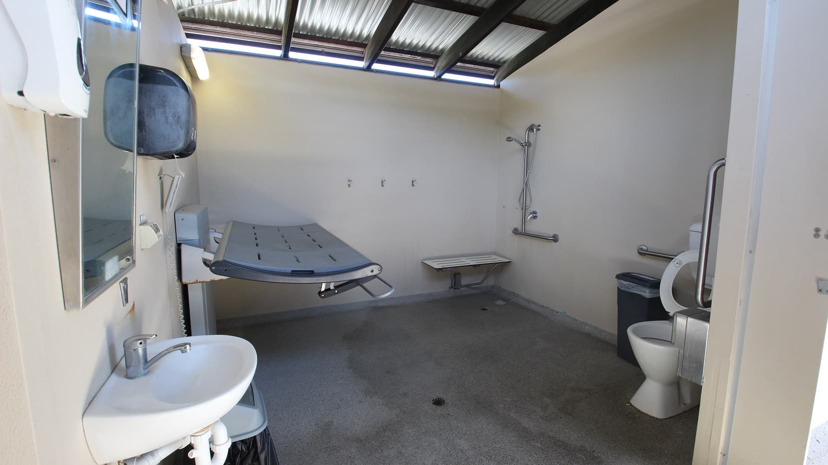 An adult size change table is located next to the Indoor 25m pool. A functional room including the table and toilet with a significant number of handrails and supports.