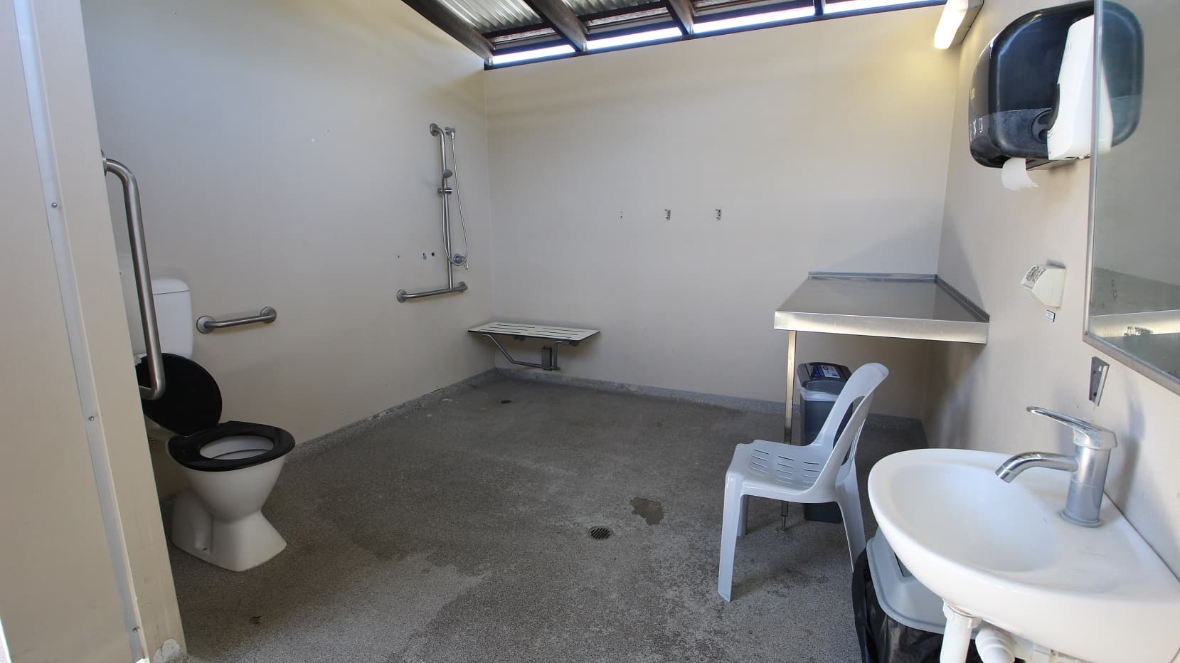An adult size change table is located next to the Indoor 25m pool. A functional room including the table and toilet with a significant number of handrails and supports.