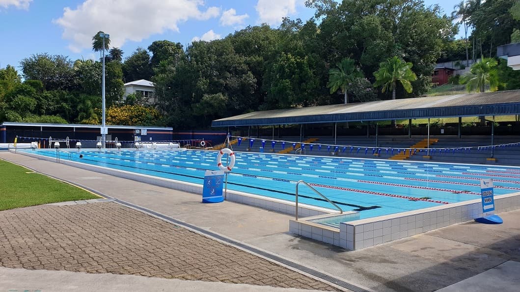 The outdoor 50m pool at the Nambour Aquatic Centre. The pool is 8 lanes wide and set amongst dense green foliage and a spectator stand on the far side of the pool.