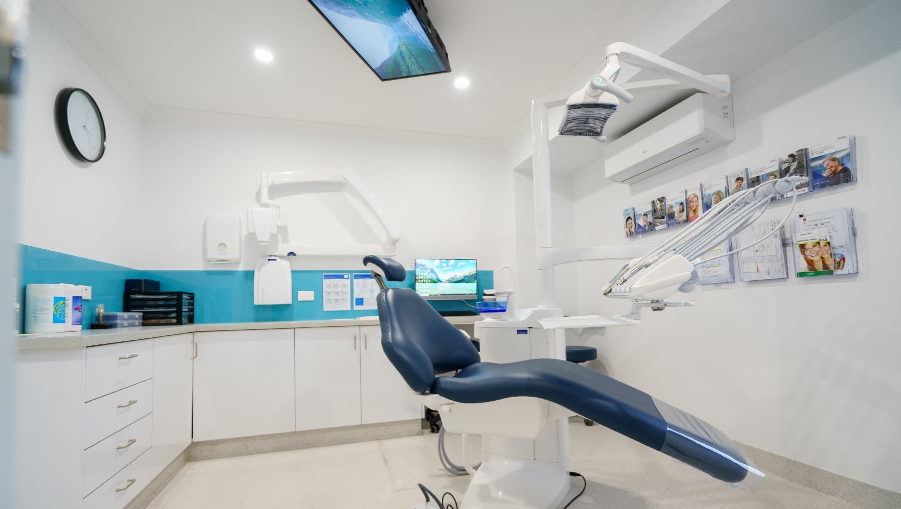One of the rooms in the clinic that appears to be neat and well-organized. It is a room without a door and instead a wide opening that leads you to another section or room of the building. It has walls painted white and a sky-blue accent in between the built-in cabinet and the clinic desk. The clinic files are arranged well in paper racks near the glass window with black rails. This room also has a comfortable office chair, desktop and telephone for the clinic staff.
