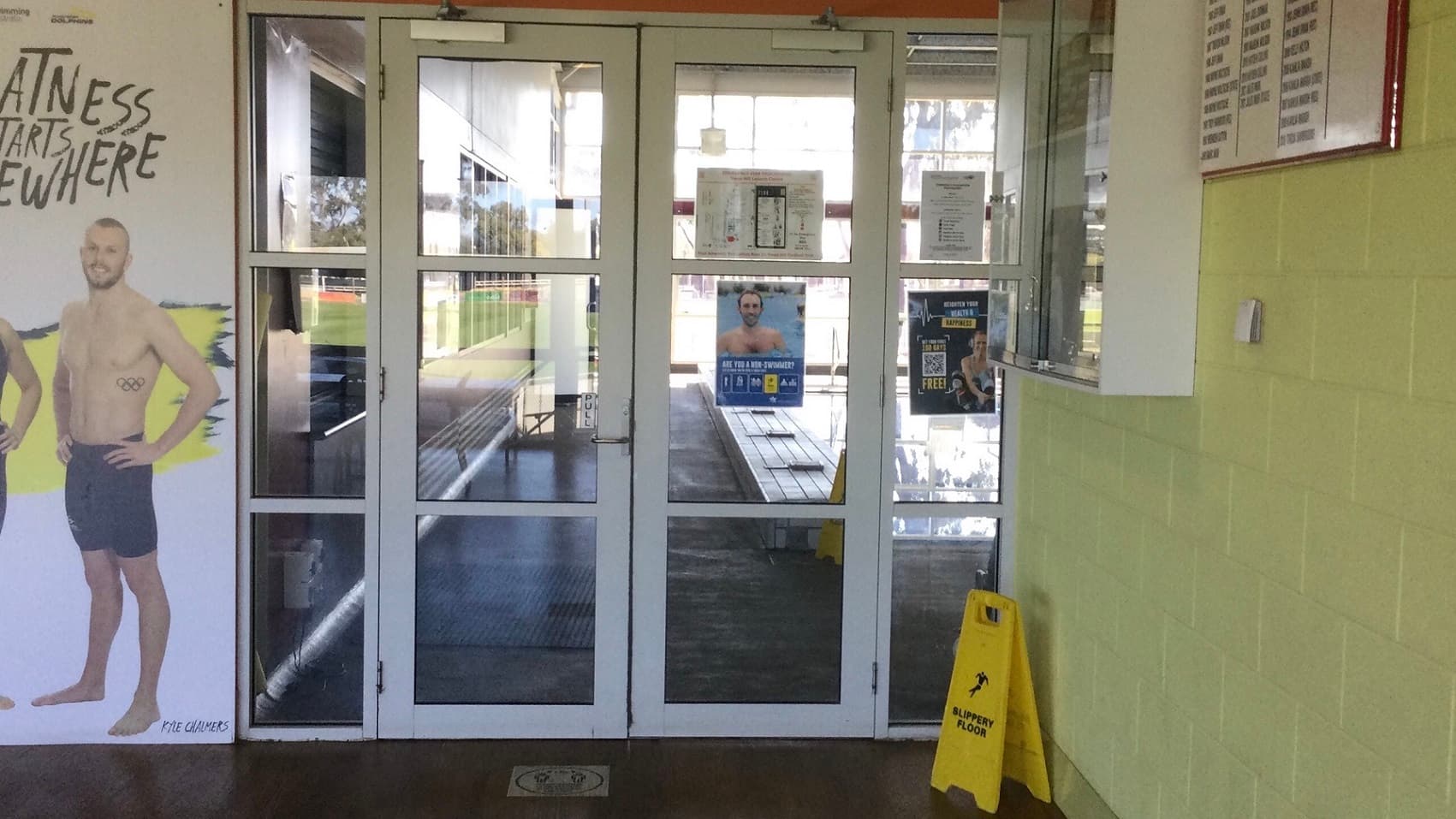 This is a closer look of an open fitness club section of Swan Hill Leisure Centre. The room has a grey ceiling. A variety of pin-loaded machines, free weights, and cardio apparatus are available in this fitness area. A view from outside can be seen while working out through the gym glass walls.