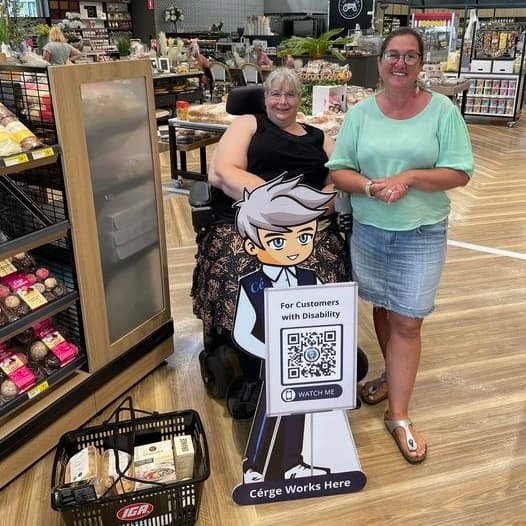 Two women in a grocery aisle stand by a cartoon cutout with a QR sign.