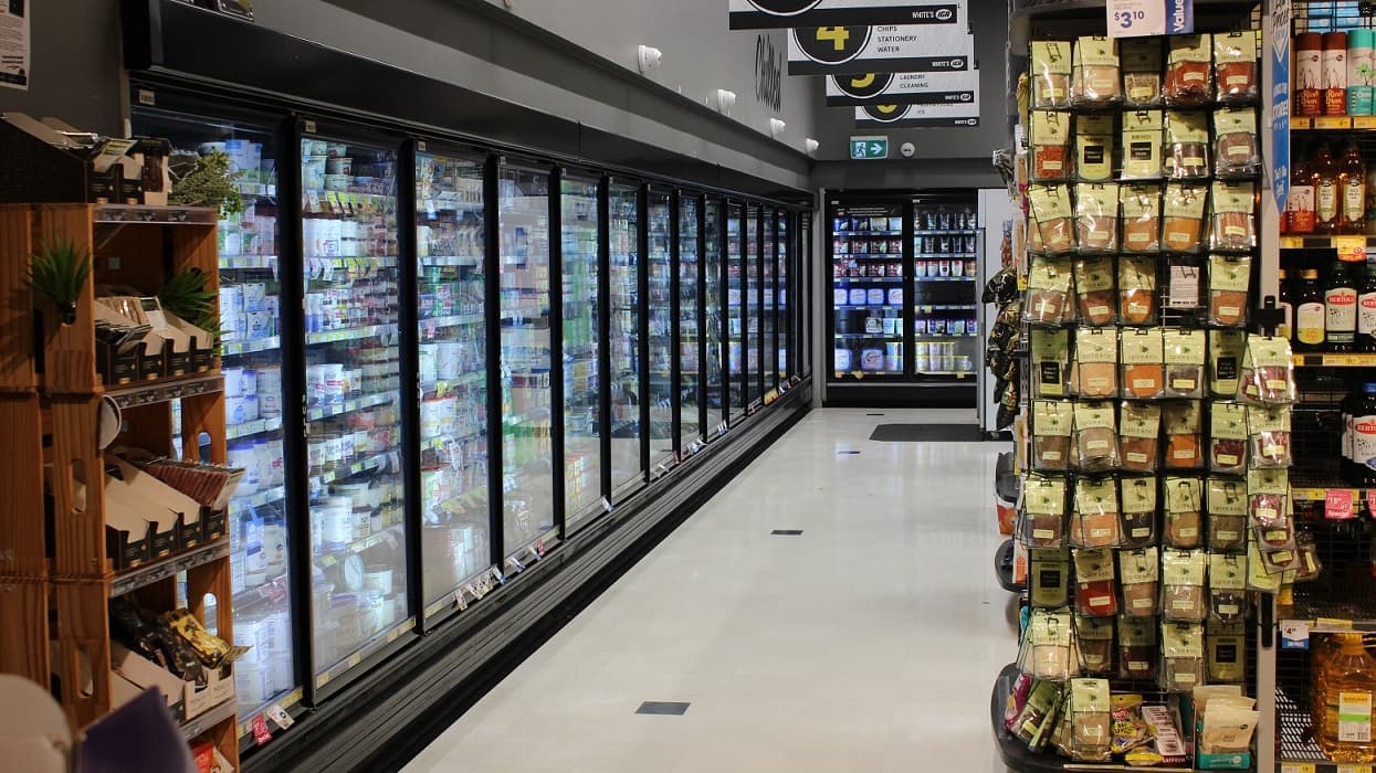 This is the corner section of the grocery store where a variety of chilled products are placed in a walk-in cold storage and chillers. The floor color is white and the walls in this section are painted grey.