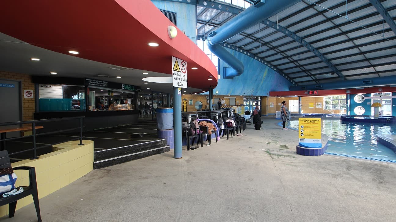 The seating area outside the Swell Café is near the children’s pool at the Aquatic centre in Whitlam Leisure Centre. The left side of the café is a brick wall and the door which can only be accessed by staff members. The ceiling is painted with grey and red paint with peculiar fluorescent sizes.