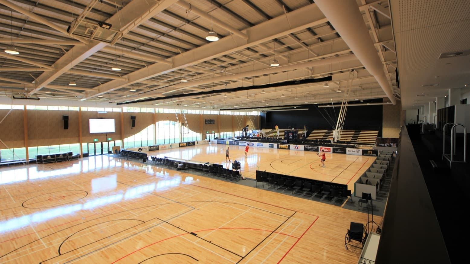 The stadium’s two other courts with varnished timber flooring. These courts have ceiling suspended adjustable basketball goals. The other end of the court is dedicated to the guest who will watch the games as there are several rows of seats available. The partition of the two courts has a black floor dedicated for single-row chairs. This section offers a high-level atmosphere because of the ceiling’s white paint with a combination of good lighting.