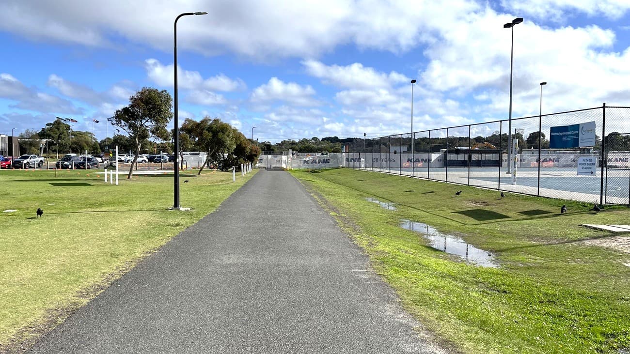 View of the path from Wurdi Baierr stadium towards the disabled car parking. Here, the netball courts are on the right and the oval is on the left. You might hear netballer's playing on this section of path.