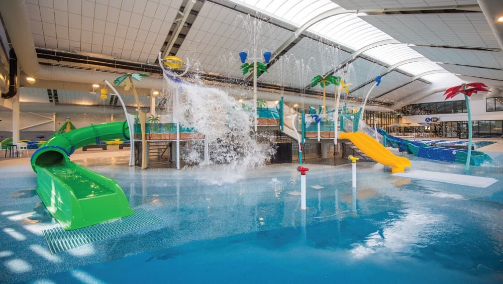 The Kids Waterslides and Splash play zone at Yawa Aquatic Centre. It has a beach theme with artificial coconut trees. Water splashing from different tubes placed within the pool and green, blue, and yellow slides will surely attract kids to play. Access to the slides is through the stairs at the back and front.