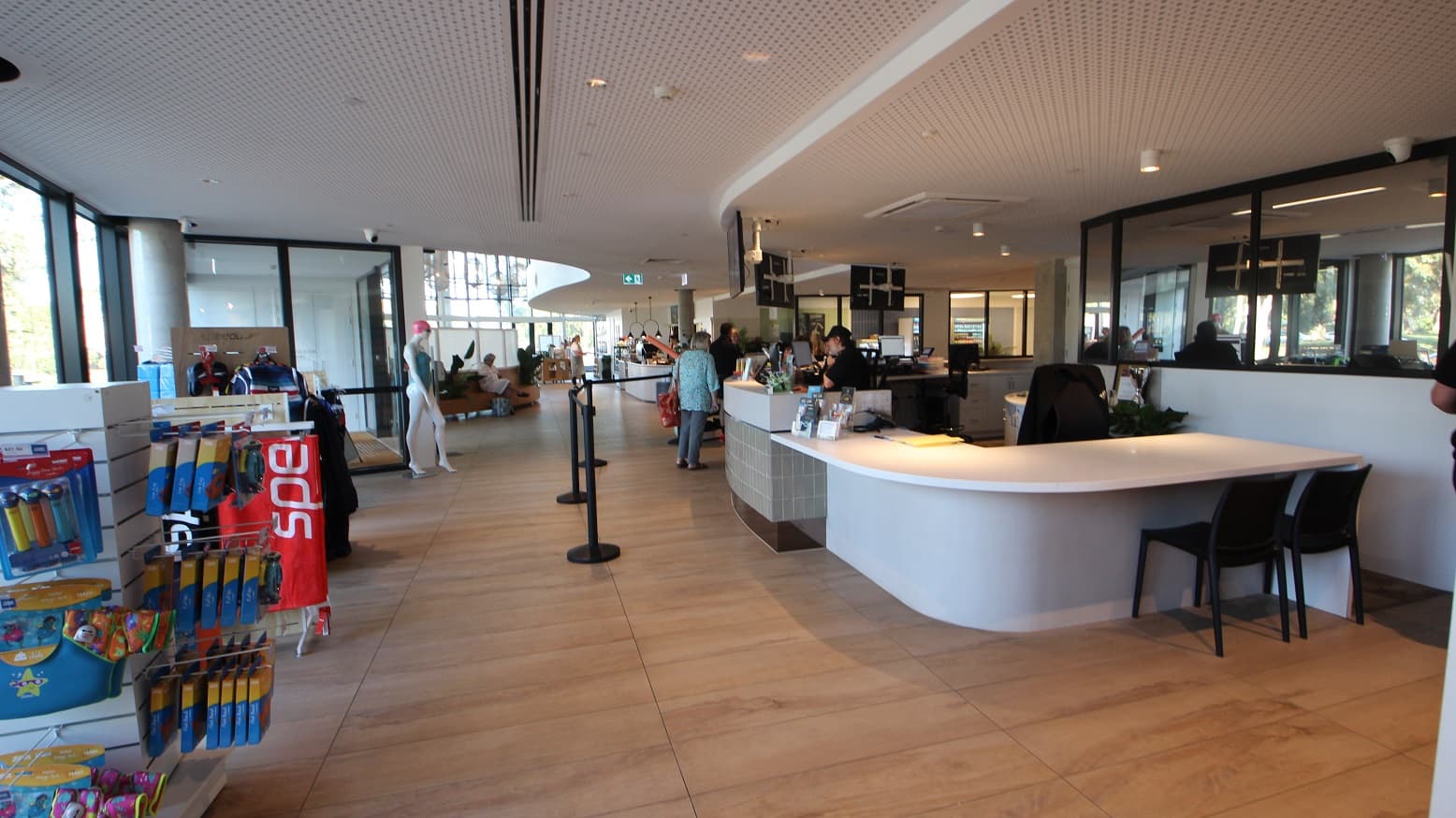 Right after the entrance glass doors is a small retail section for swim gear as well as swimming suits. Reception staff at Yawa Aquatic Centre are wearing black polos and black caps etched with YAWA, while the Café staff are wearing white shirts with brown aprons. Mounted on the ceiling within the reception area are three televisions.